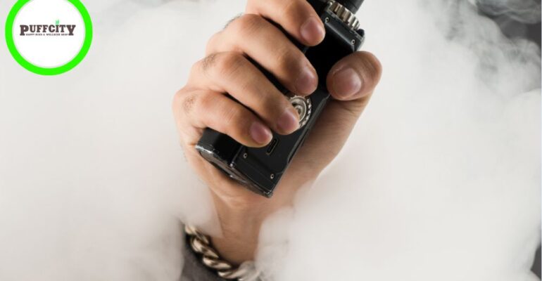 A hand with unique different accessories on her wrist with a black color vape with a smoky white background.