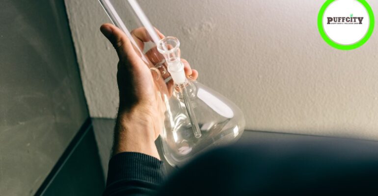 A man holds a glass water pipe in his hand.