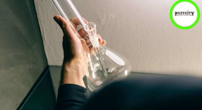 A man holds a glass water pipe in his hand.